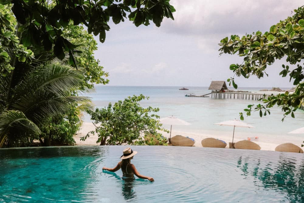 Eine Frau schwimmt in einem Infinity-Pool im Constance Halaveli Resort auf den Malediven.